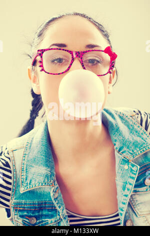 Giovane donna soffiando bubblegum, intenzionalmente tonica. Foto Stock