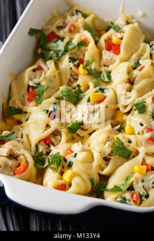 Cotto al forno conchiglioni pasta farcita con pollo e funghi e verdure close-up in una teglia su una tavola verticale. Foto Stock