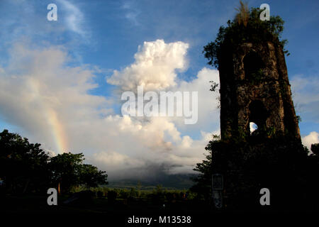 Mt. Mayon eruttate (arcobaleno su lato sinistro) nella mattina in anticipo con la cenere vulcanica cade dal punto di vista di Cagsawa Parco Nazionale in Daraga, Albay, Bicol a gennaio 26, 2018. L'Istituto filippino di vulcanologia e sismologia (PHILVOLCS) dichiarati numero di avviso 8 e una più ampia della zona di pericolo a 8 chilometri dopo le esplosioni la continua attività attive del vulcano di questo passato diversi giorni. Secondo i rapporti è un totale di 74.000 persone sono colpite e 100 milioni di euro di danni nei terreni agricoli secondo del dipartimento dell'Agricoltura (DAR) (foto da Gregorio B. Dantes Jr./P Foto Stock