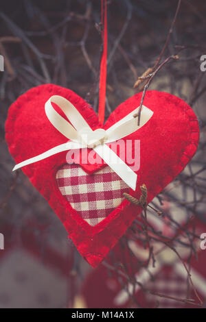 Tessuto Artigianale cuore appeso a un ramo, equo merci, Decorazione per albero di Natale o il simbolo di San Valentino Foto Stock