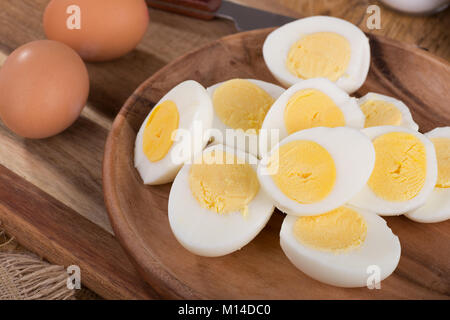 Uova sode a fette su un piatto di legno Foto Stock