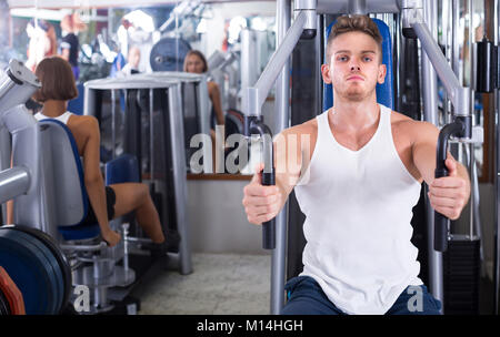 Adulto ben addestrato uomo utilizzando pec deck palestra macchine in ambienti chiusi Foto Stock