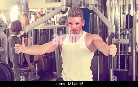 I giovani europei ben addestrato uomo utilizzando pec deck palestra macchine in ambienti chiusi Foto Stock