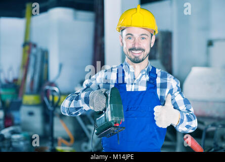 Sorridente uomo di lavoro mettere in pratica le sue abilità con potenza il puzzle in officina Foto Stock