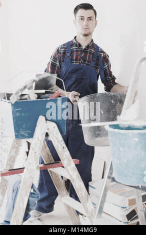 Repairman mescolerà putty nel processo di riparazione di casa. Foto Stock