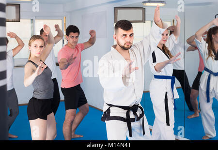 I giovani adulti di tentare di nuovo master si sposta durante il karate class Foto Stock