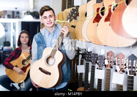 Europeo teenage ai clienti di decidere su appositi chitarra acustica nel negozio di chitarra Foto Stock