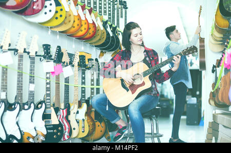 Sorridente teenager italiani ai clienti di decidere su appositi chitarra acustica nel negozio di chitarra Foto Stock