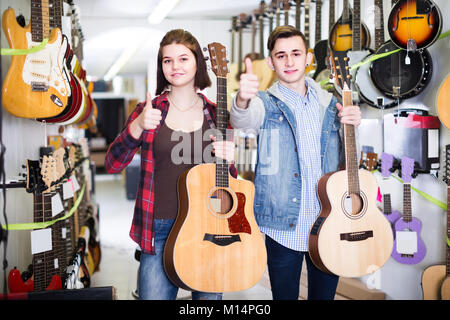 Sorridente clienti adolescenti decidere su appositi chitarra acustica nel negozio di chitarra Foto Stock