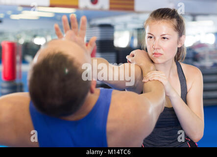 Giovane donna e il suo trainer sono la pratica punzoni sul self-defence corso in palestra Foto Stock