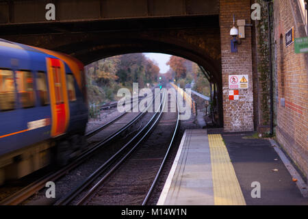 Una rampa di Southwestern velocità dei treni da con l'effetto di sfocatura di movimento. Muro di mattoni e cartelli di avvertimento sono in una messa a fuoco nitida. St Margrets, Richmond, Inghilterra Foto Stock