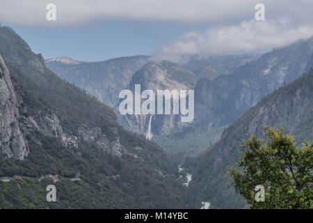 Vista della Valle di Yosemite, Cascate di Bridalveil, fiume Merced e sulle montagne circostanti, con nuvoloso cielo blu, nel Parco Nazionale di Yosemite Foto Stock