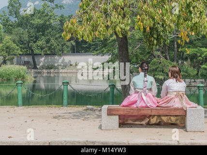 Due donne in coreano tradizionale abbigliamento seduta su una panchina, godendo di una splendida vista sul mare, presso il Palazzo Gyeongbokgung, Seoul, Corea del Sud Foto Stock