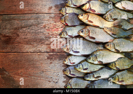 Pescato fresco carp pesce su legno. La cattura di pesci di acqua dolce su uno sfondo di legno. Un sacco di orate pesce, carassio o roach su legno naturale dello sfondo. Backgro Foto Stock