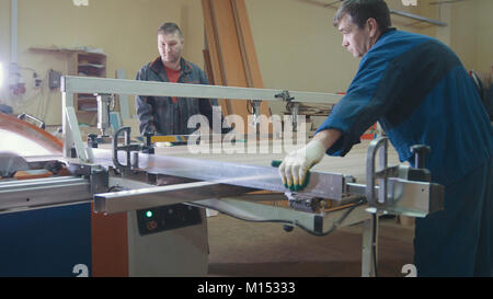 Lavoratori carpentieri sono il taglio di dettaglio in legno sulla sega elettrica alla fabbrica di mobili Foto Stock