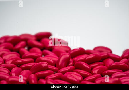 Messa a fuoco selettiva del rene rosso zucchero forma compressa rivestita pillole su sfondo bianco con spazio di copia Foto Stock