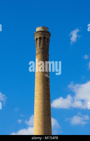Un mattone di alto camino industriale contro un cielo blu Foto Stock
