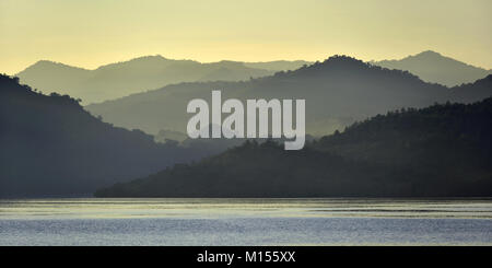 Twilight prima del sorgere del sole sulla costa dell'oceano. Oceano e Montagne Paesaggio presso la mattinata nebbiosa. Isola di Komodo. Molucche, indonesiane Molucche, Spice Isla Foto Stock