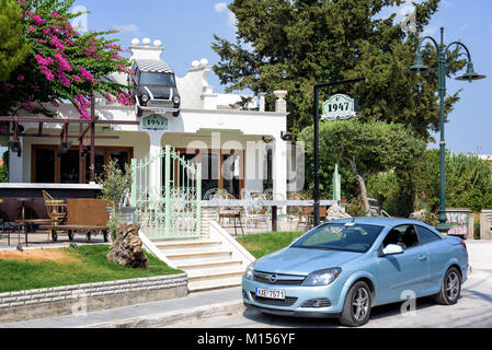 FALIRAKI, Grecia - Agosto 2017: piccola strada ristorante decorato con mini cooper auto sospeso su un tetto a Faliraki città sull isola di Rodi, Grecia Foto Stock