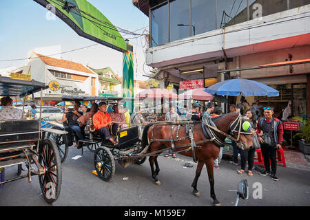 Carrozza a cavalli usati come trasporto in movimento lungo Pajeksan Street (Jalan Pajeksan). Yogyakarta, Java, Indonesia. Foto Stock