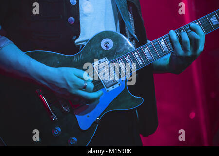 Il chitarrista suona la chitarra elettrica su un palco, foto con morbida messa a fuoco selettiva Foto Stock