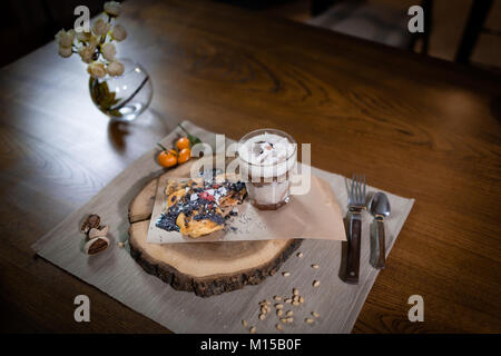 Bel piatto per una colazione elegante vassoio in legno Frittelle e semifreddo con frutti decorate con condimenti sul tavolo. Pronto a mangiare. Close-up Foto Stock