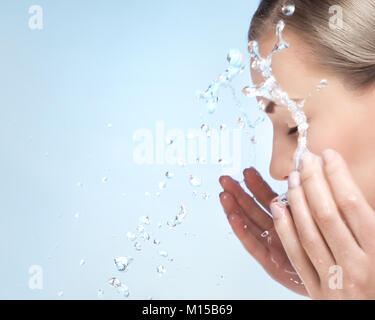 Una donna sta lavando la faccia con acqua fredda, pulire la pelle dopo il trucco, usando anti acne o anti invecchiamento agente, coccole e cure di bellezza concetto Foto Stock