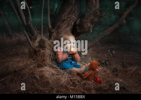 Baby girl è seduto sotto un albero e mangiando un apple. Foto Stock