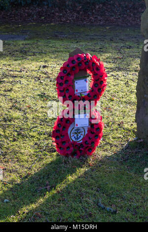 Due corone di fiori di papavero alla chiesa di San Lorenzo, Mereworth, Kent, retroilluminati da sole d'inverno Foto Stock