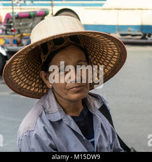 Una donna anziana con un tradizionale hat a Bangkok Foto Stock