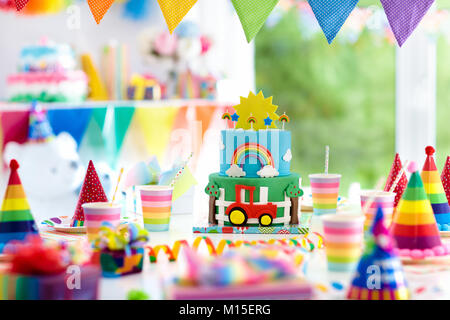 Kids festa di compleanno. Bambino soffiando le candeline sulla torta  colorati. Casa decorata con bandiera arcobaleno banner, palloncini. Animali  da fattoria festa a tema. L Foto stock - Alamy