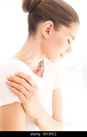 Modello rilasciato. Giovane donna nel dolore strofinando il spalla. Foto Stock
