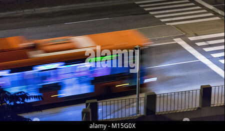 Bus sfocata si muove su una strada di città di notte Foto Stock