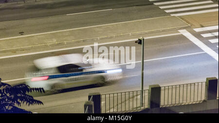 Sfocata auto della polizia si muove su una strada di città di notte Foto Stock