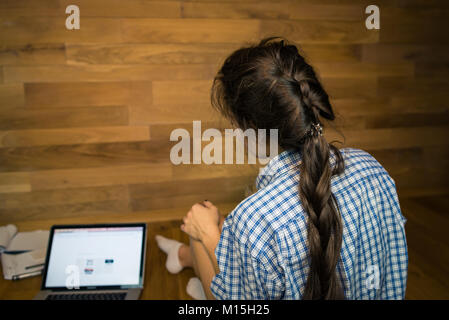 Giovane donna dopo la giornata di lavoro si siede sul pavimento presso l'ufficio domestico. Giovane imprenditrice di lavoro con documenti e il computer portatile Foto Stock