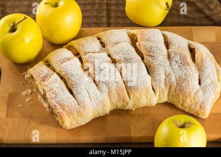 In casa strudel di mele (torta di mele con pasta sfoglia, cannella e uva passa su un tagliere di legno Foto Stock