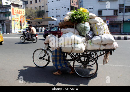 L'uomo spingendo caricato di risciò ciclo di Hyderabad, India Foto Stock