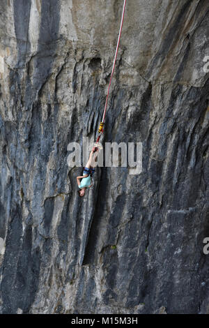 Ragazza giovane bungee jumper appeso a una fune, le rocce scure della grotta Prohodna visto a sfondo Foto Stock