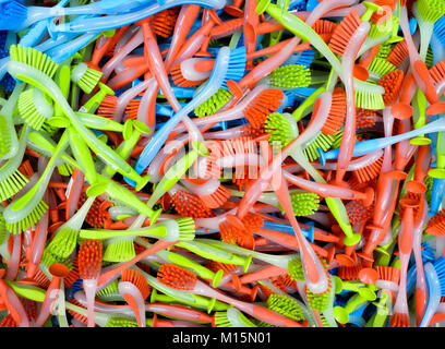 Circa un centinaio di plastica colorata lavastoviglie spazzole impilati in modo casuale sulla parte superiore di ogni altro, rosso, verde e blu Foto Stock