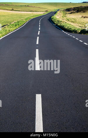 Un grigio asfalto stradale del paese con forti linee bianche nel medio e basso punto di vista rende la strada e linee bianche grande in primo piano che conduce a Foto Stock