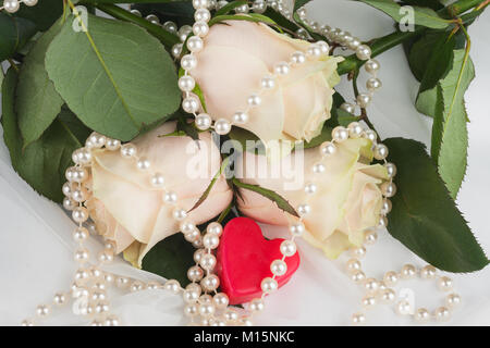 Cuore rosso circondato da rose e perle. Concetto di dolci del giorno di San Valentino Foto Stock