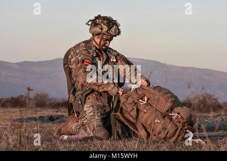 Un jumpmaster dal 173rd Airborne Brigade ispeziona il suo equipaggiamento immediatamente dopo lo sbarco sulla zona di caduta nel nord Italia. Foto Stock