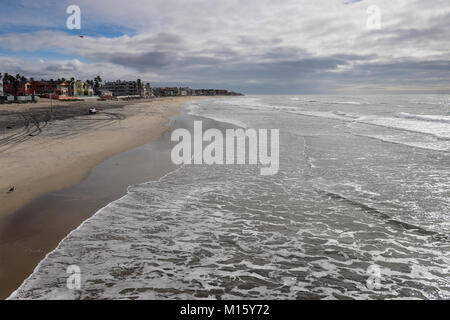 Vista la bellissima e ampia spiaggia sabbiosa dal molo Imperial Beach in California con la bassa marea,quando la sabbia è bagnato,schiumosa e riflessiva, cielo tempestoso Foto Stock