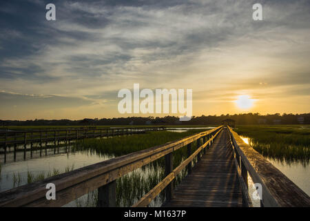 Lunga passerella in legno pier su marsh ad alta marea con un fantastico del cielo della sera e al tramonto Foto Stock