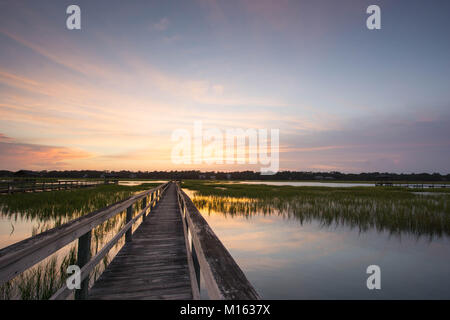 Lunga passerella in legno pier su marsh ad alta marea con un fantastico del cielo della sera e al tramonto Foto Stock