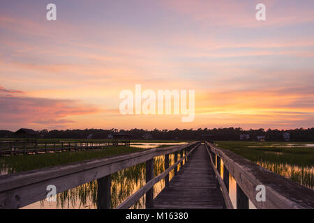 Lunga passerella in legno pier su marsh ad alta marea con un fantastico del cielo della sera e al tramonto Foto Stock