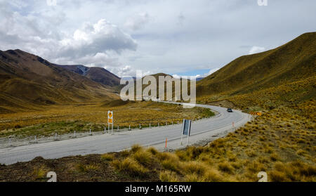 Strada di Montagna con erba secca in autunno sul Lindis Pass nell Isola del Sud della Nuova Zelanda. Foto Stock