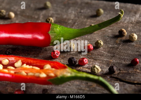 Spezie: red hot chili pepper con grani di pepe colorato su legno rustico sfondo Foto Stock