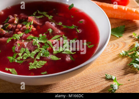 Tradizionale rumena borscht di barbabietole in bianco ciotola sul tagliere di legno Foto Stock