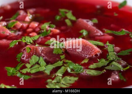Close up tradizionale Rumena borscht barbabietole con verde prezzemolo nel recipiente bianco Foto Stock